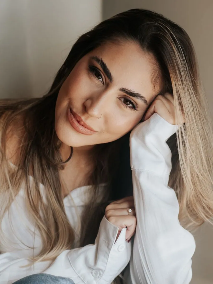 Dra. Júlia Tôrres sorrindo, com a mão no rosto